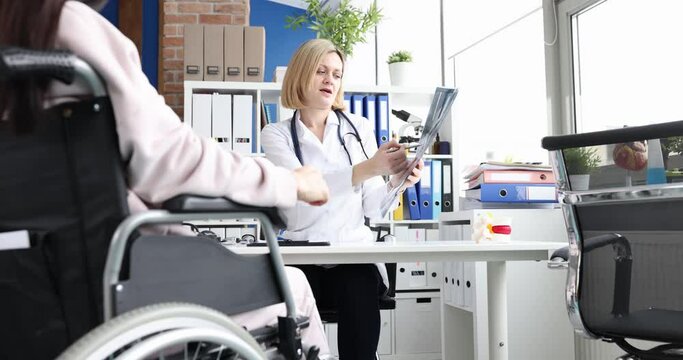 Professional doctor consults patient in wheelchair checks x-ray. Spinal injury and treatment concept