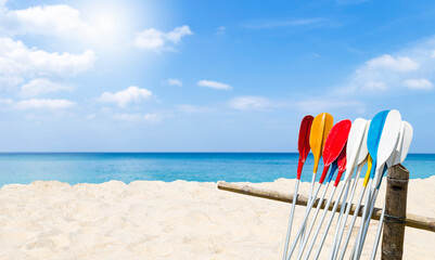 Colorful oars on old bamboo fence with space on sandy beach background, Tropical summer concept,...