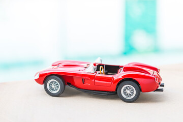 Fototapeta premium Sport car model on swimming pool edge with space on blurred background, outdoor day light