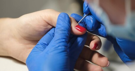 Manicurist covers client nails with red nail polish. Beauty salon and manicure pedicure concept