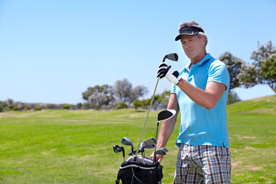 Senior, man and golf club on green grass, field or lawn for sports, choice or selection on course. Mature male person, golfer or player thinking, picking or choosing for score or point in nature