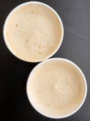 Two cups of coffee. Two paper glasses with coffee on a black background