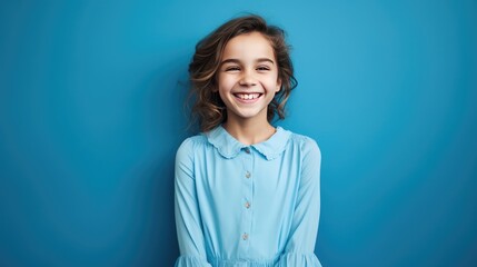 Fototapeta premium Portrait of a cute little girl smiling on a blue background.Portrait of a beautiful girl, a schoolgirl. The concept of advertising.