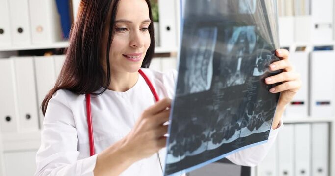 Woman doctor looking at xray of spine in clinic 4k movie slow motion. Diagnosis and treatment of intervertebral hernia concept