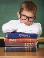 Frustrated boy child, books and portrait in classroom for knowledge, information and studying at...