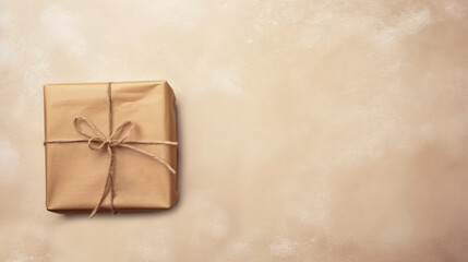 Gift wrapped in brown paper and tied with twine on beige old plastered background, minimalism, retro style. Gift for holiday or celebration: birthday, Valentine's day,  wedding. Top view. Copy space