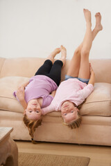 Girl kids, sisters and upside down on couch, bonding for love and care at family home with trust...