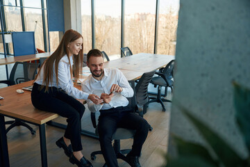 Obraz premium Showing information in the phone. Man and woman employees are working in the office