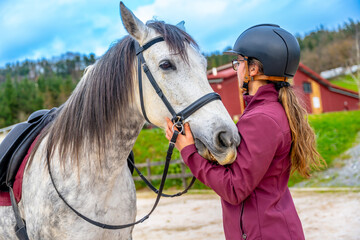 Woman with her horse in equestrian center