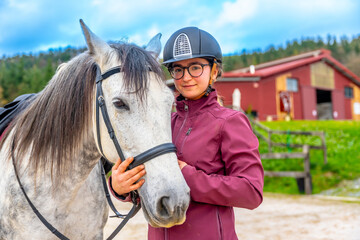 Young girl with her white horse in an equestrian center