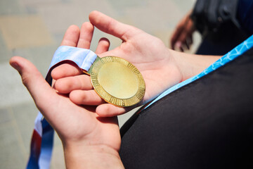 The medal is in the hands of an athlete, a close-up of the hands. A clean surface for applying designs or inscriptions