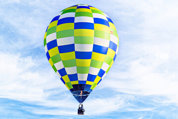 Colorful hot air balloon flying over blue sky with white clouds