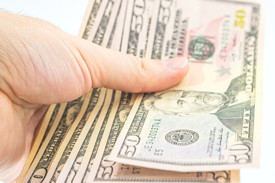 Man hand with dollars isolated on a white background. Businessman gives fifty dollars. Concept of tips and cash in America. A bundle of dollars, bribe, illegal traffic. Several 50 dollar bills in hand
