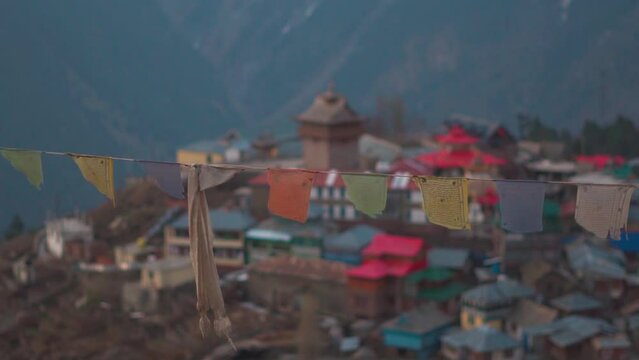 Closeup shot of Buddhist prayer flag waving in front of the Kalpa village during early morning at Kinnaur in Himachal Pradesh, India. Buddhist prayer flags wave in front of village in the mountains.