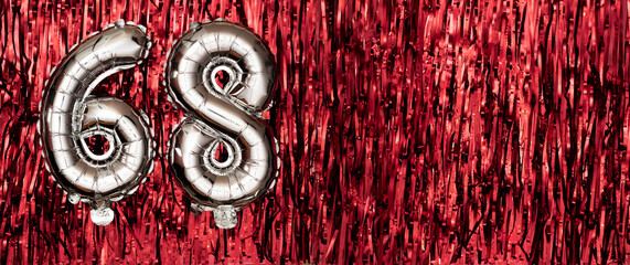 Silver foil balloon number, digit sixty-eight on red background. Birthday greeting card with...