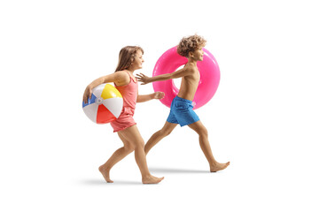 Playful kids in swimwear running and carrying a swimming ring and a ball - obrazy, fototapety, plakaty
