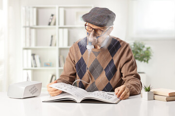Elderly man using a nebulizer and reading a book at home