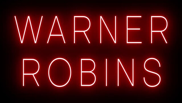 Flickering red retro style neon sign glowing against a black background for WARNER ROBINS