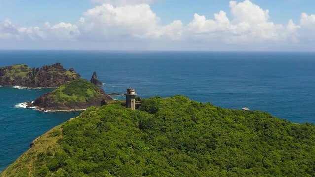 Aerial view of lighthouse on a hill and blue ocean with islands. Cape Engano. Palaui Island. Santa Ana Philippines.
