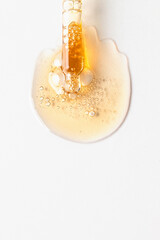 Top view of dropper pipette with oil serum liquid and drops smear with bubbles on white background