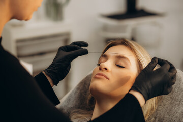 Fototapeta premium Young woman having eyebrow correction procedure in beauty salon