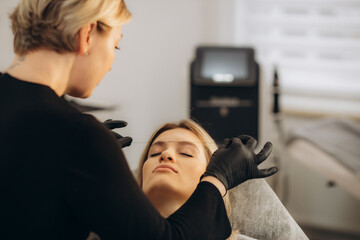 Young woman having eyebrow correction procedure in beauty salon - obrazy, fototapety, plakaty