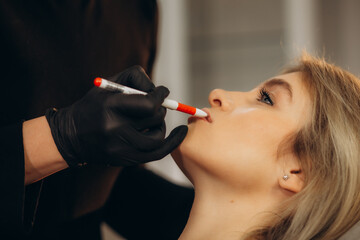 Beautiful young girl in beauty salon. Woman having permanent tattoo makeup on her lips.