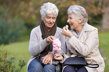 Elderly women, eating and snack in park with candy floss, happy and together to relax on retirement...