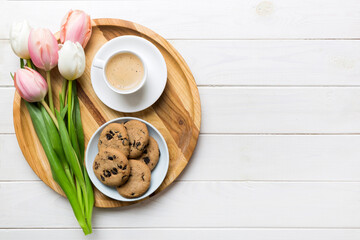 Cup of coffee mug with coffee, cookies and tulips on a colored background. Greeting spring card top view