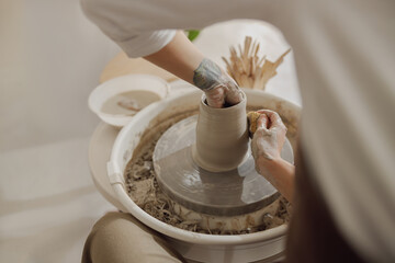 Close up of artisan's hands shaping clay bowl in pottery studio. Pottery art and creativity
