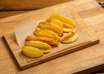 Potato slices fried on a wooden board