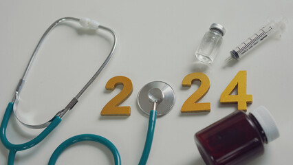Stethoscope and gold numbers 2024 on white background. Concept of health care in the New Year....