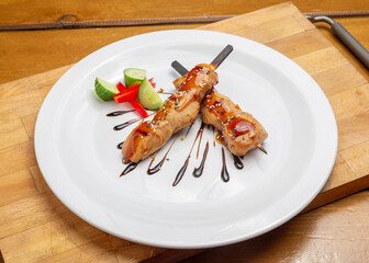 Chicken kebab with teriyaki sauce on a plate on a wooden board