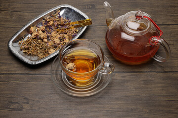 Make mix pour herbal floral tea drink transparent glass teapot to teacup twister pick up put rustic wooden table