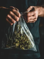 Fotobehang person putting weed in a plastic bag © Dismal Creative