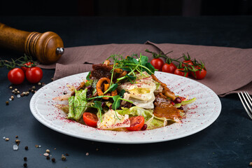 Georgian cuisine salad with bacon, lettuce, cherry tomatoes, onion, pomegranate seeds and pepper.