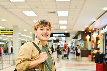 Handsome Asian male tourist waiting for flight at airport lounge. Travel and transportation concept