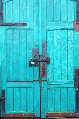 Vintage greenish wooden door closed with a bolt and padlock.