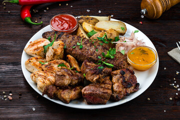 Portion barbecue with beef, pork, chicken, potatoes, onions and sauce in plate.