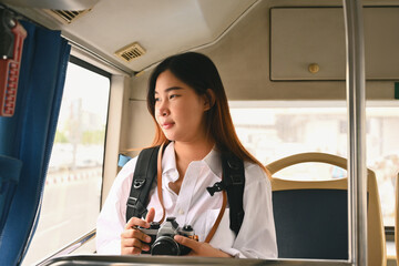 Attractive young woman traveling and looking through the bus window. Commuting and lifestyle concept