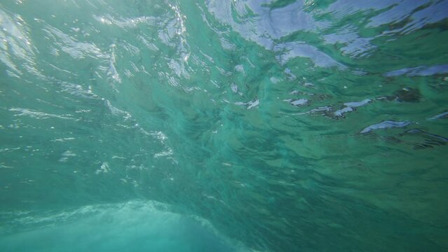 Surfer riding on a wave in crystal clear water in Byron Bay Australia shot from underwater in slow motion 