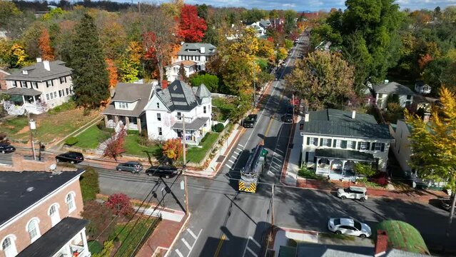 Fire truck on town street. Fast paced aerial tracking shot through historic streets lined with old homes in autumn in USA.