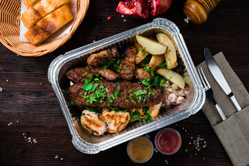 Portion barbecue with beef, pork, chicken, potatoes, onions and sauces in box, takeway.