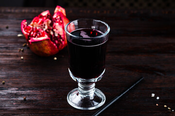 Freshly squeezed pomegranate juice in a glass on wooden table.