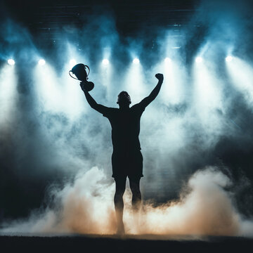 Silhouette of a football player celebrating with a trophy on stage