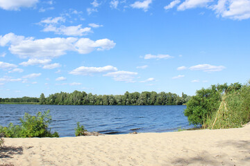 Summer landscape on the shore of the lake, blue sky with clouds