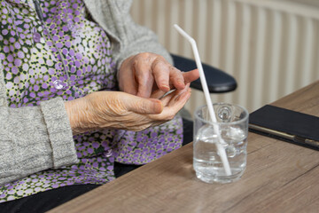 Senior woman's hands with medication and a glass of water