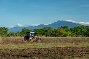 Obraz premium Blue sky over tractor plowing a field with Baru volcano in the background, Chiriqui, Panama, Central America - stock photo