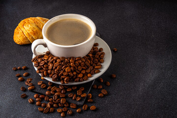 Obraz na płótnie Canvas Black espresso coffee cup with croissant and coffee beans, simple traditional french breakfast 