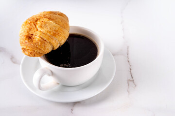 Black espresso coffee cup with croissant and coffee beans, simple traditional french breakfast 